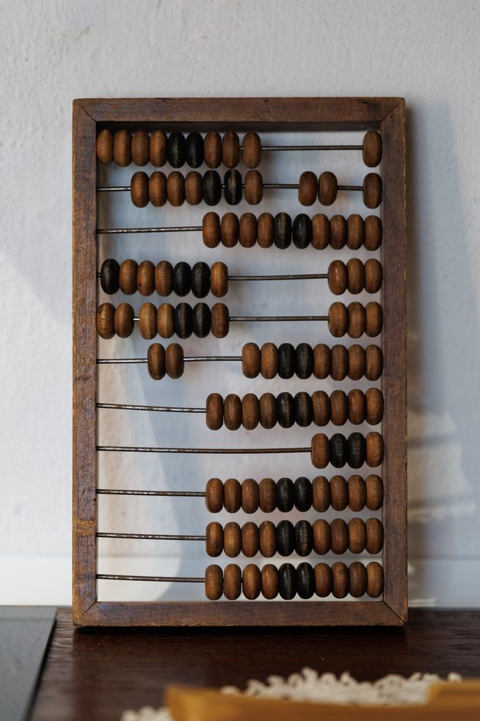 Vintage wooden abacus with brown and black beads on a white background.