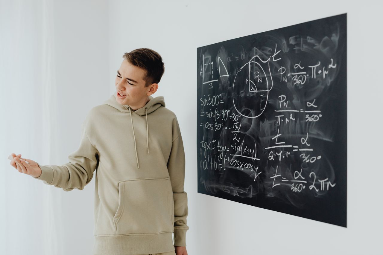 Crafting Captivating Headlines: Your awesome post title goes here Enthusiastic teen boy in a hoodie teaching math on a blackboard.